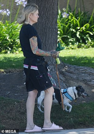 She paired it with black cargo shorts, a matching hip bag and pink slide sandals