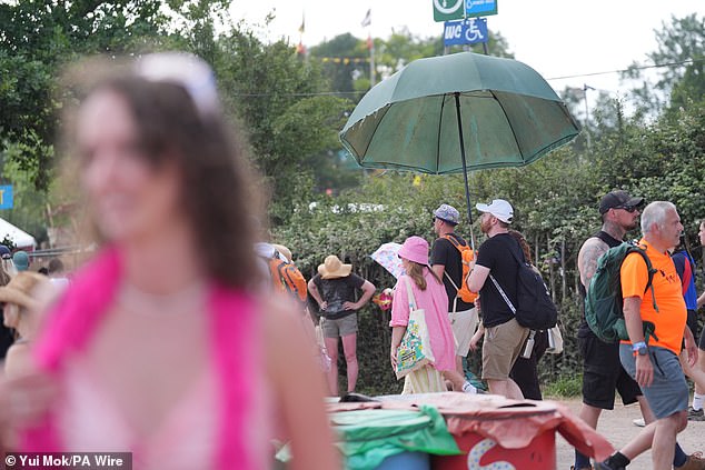 A festivalgoer holds a parasol to shield from the sun, near the West Holts stage during the Glastonbury Festival
