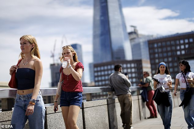People cross London Bridge and hydrate amid boiling temperatures in the capital