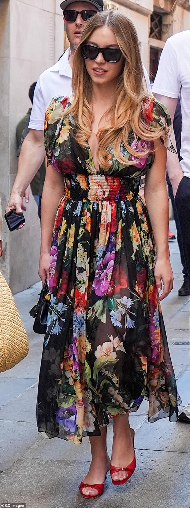 Sydney Sweeney, 27, dressed perfectly for the occasion, wearing a flowing floral sheer dress with a plunging neckline. She opted to wear her hair down with curled her ends - and decided to pair her dress with red, open-toed kitten heels