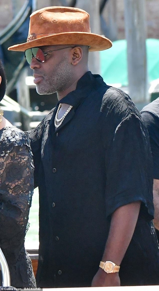 Kris Jenner's long-time beau Corey Gamble, 44, looked more cartoonish than anything as he stepped out besides Kris wearing a giant suede hat. He paired his black button-down collared shirt with a gold chain, gold watch, and aviator sunglasses