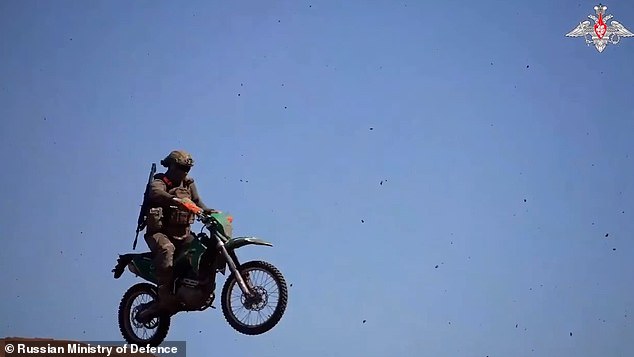 In April, Russia's ministry of defence released a video showing a paratrooper with a gun over his shoulder riding around a motocross track while explosions detonated around him