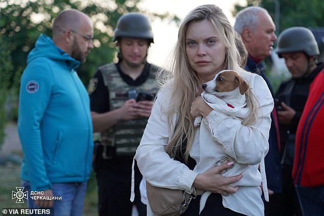 A resident holds her dog at the site of an apartment building damaged during Russian drone and missile strikes, amid Russia's attack on Ukraine
