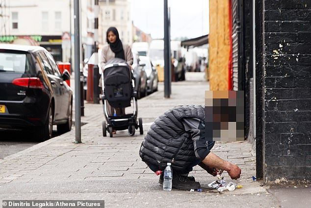 MailOnline observed one man appearing to inject himself in the street while shocked pedestrians looked on