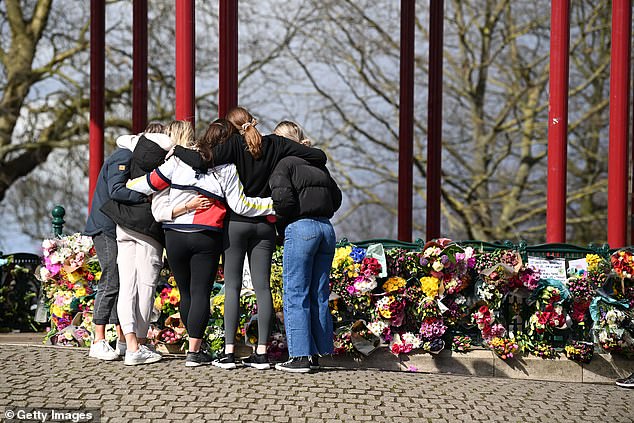 Pictured: a group of women hug as they stand in front of tributes for Sarah Everard