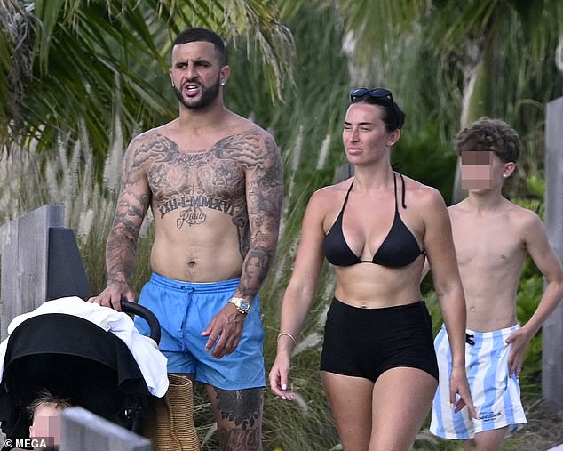 The Manchester City ace put his toned frame and intricate tattoos on full display as he went shirtless in a pair of vibrant blue board shorts