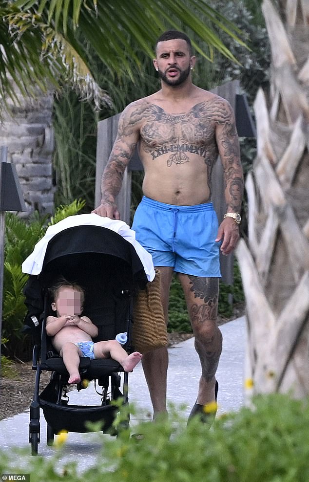 The Manchester City ace put his toned frame and intricate tattoos on full display as he went shirtless in a pair of vibrant blue board shorts