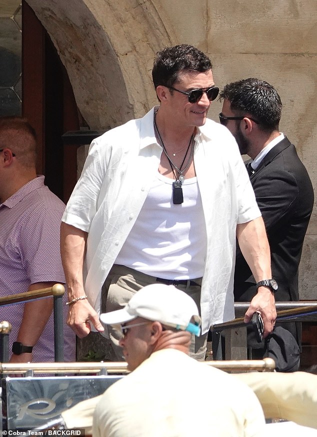 Orlando flashed a wide grin as he climbed aboard, wearing a button-up shirt left open to reveal a white vest underneath and several pendant necklaces