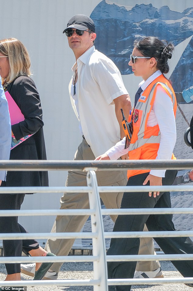 Bloom looked relaxed in an unbuttoned short sleeved white shirt over a tight fitting T-back T-shirt and tan khakis. He wore white sneakers and placed a black billed cap over his dark curls