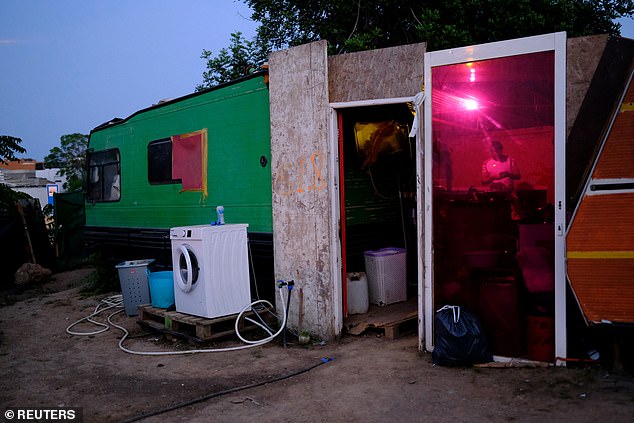 Shocking images show how locals are living in tents and caravans with their families while revellers enjoy luxurious accommodation. Pictured: Richard, 35, worker of construction of housing, stands inside his shack, where their family lives at a makeshift settlement