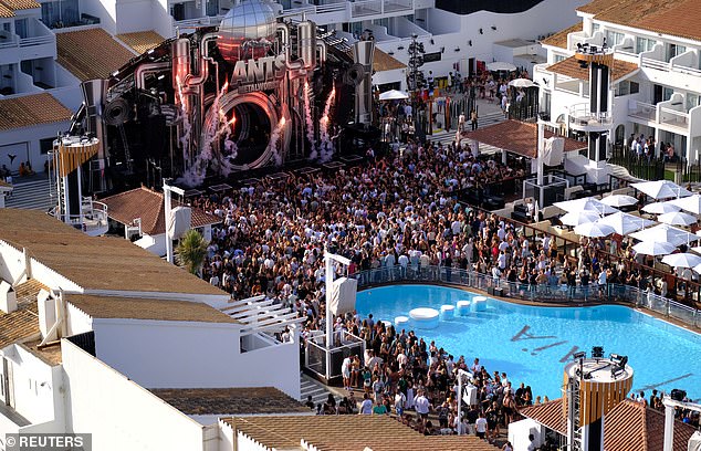 Sobering images reveal the stark contrast between island residents struggling to make ends meet and tourists enjoying the holiday of a lifetime. Pictured: Tourists dancing inside a discotheque near Playa d'en Bossa beach during the housing crisis
