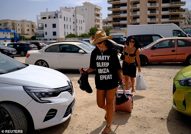Tourists push their luggages, as they walk towards their rental car