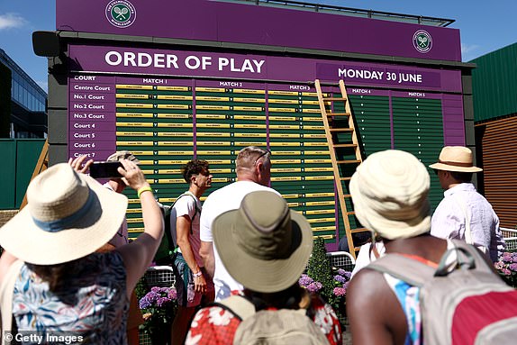 LONDON, ENGLAND - JUNE 30: Spectators take photos as the order of play board is set up on day one of The Championships Wimbledon 2025 at All England Lawn Tennis and Croquet Club on June 30, 2025 in London, England. (Photo by Dan Istitene/Getty Images)