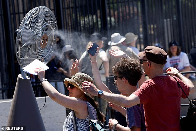 ITALY: Tourists huddle around a cooling fan outside the Colosseum in Rome as the continent saw extreme heat on Monday