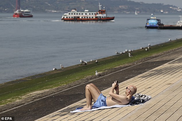 PORTUGAL: A man sunbathes near the Tagus River in Lisbon as a heat bomb hits Europe on Sunday