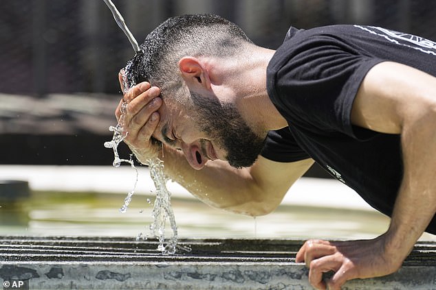 SWITZERLAND: A worker douses his head in cool water in Basel city centre on Monday