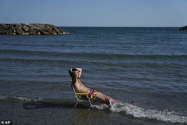 FRANCE: A beachgoer in Saintes-Maries-de-la-Mer in southern France brings his chair into cooler territory on Monday