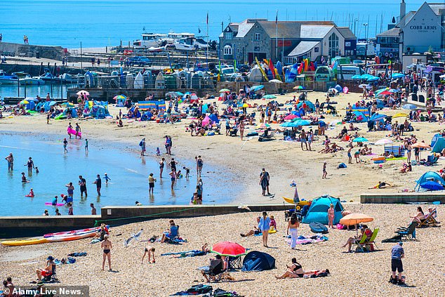 ENGLAND: Sunbathers flocked to the packed beach at the seaside resort of Lyme Regis on Monday