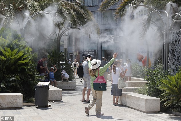 SPAIN: Tourists cool off under a cloud of mist at the Plaza de la Reina during a heat wave in Valencia on Sunday
