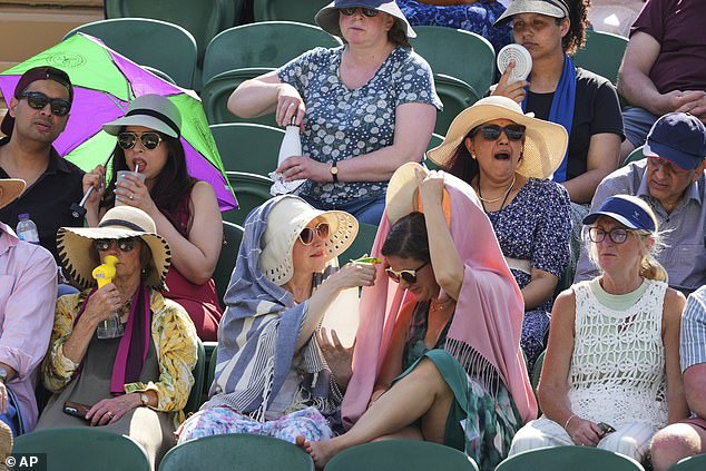 WIMBLEDON: Tennis supporters use fans and water spray to stay cool amid the red-hot weather on Monday