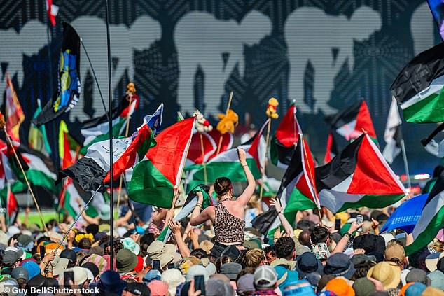 One member of Kneecap is already facing a terror charge for allegedly brandishing a flag in support of the proscribed group Hezbollah at a gig in London in November. Pictured: Their performance at Glastonbury