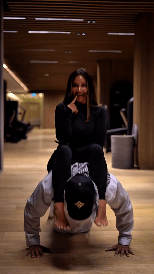 Woman sitting on a man's back as he does a handstand.