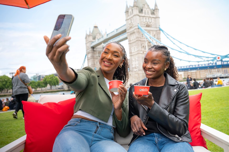 Two friends enjoy Nutella ice cream while taking a selfie in front of Tower Bridge.