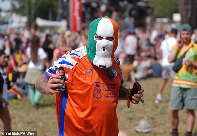 A festivalgoer wearing a tricolour Balaclava, similar to the one worn by rapper DJ Próvaí of the Irish band Kneecap, during the Glastonbury Festival