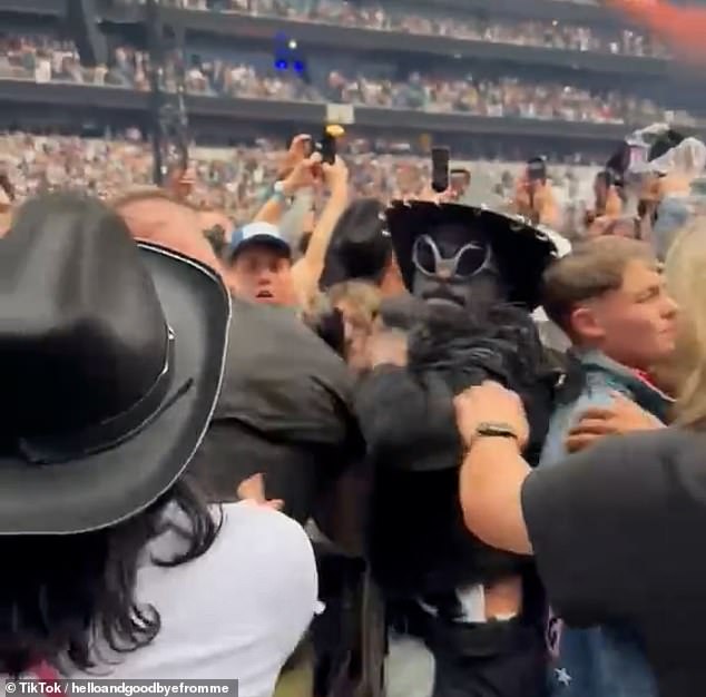 A fan dressed in glitzy black cowboy attire aggressively tackled another member of the crowd