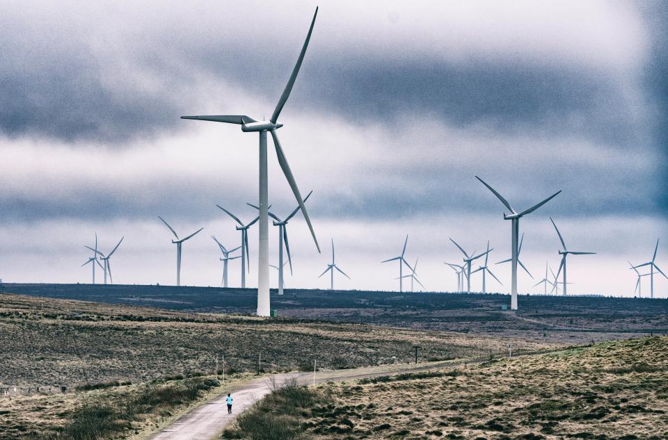 Person jogging past wind turbines at Whitelee Windfarm.
