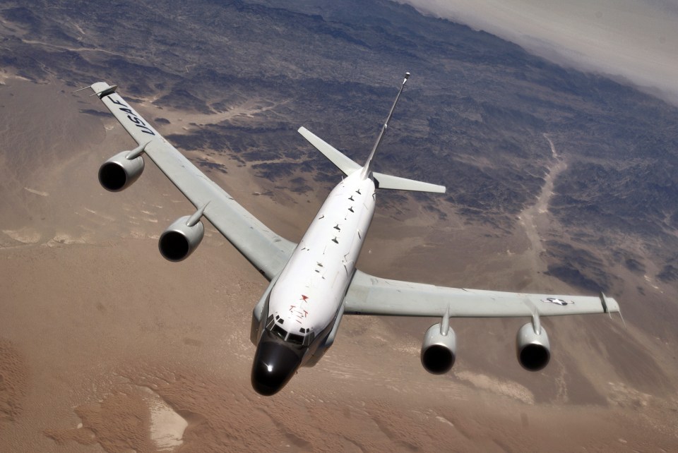 Rivet Joint aircraft in flight over a desert landscape.
