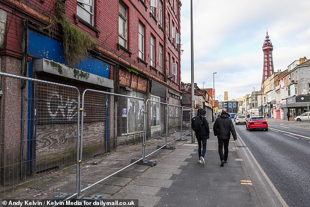 Fencing seen in front of abandoned shops in Blackpool, as the town's famous tower stands in the background