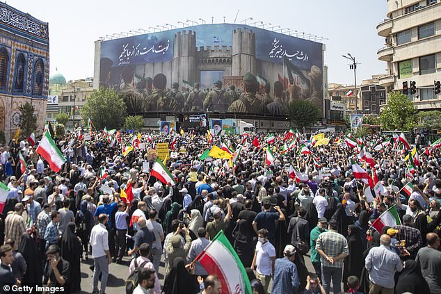 Demonstrators wave Iranian and other flags during a protest against Israeli attacks on Iran, after the Friday prayer ceremonies on June 20, 2025 in central Tehran