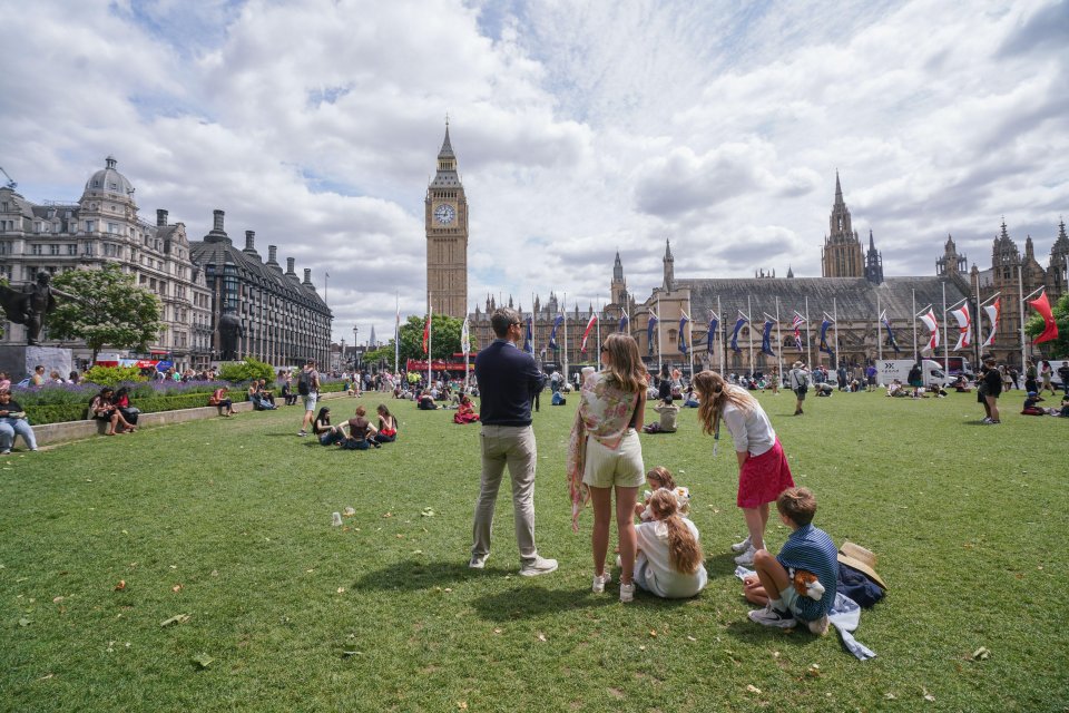 Family enjoying sunshine in Parliament Square, London, with Big Ben in the background.