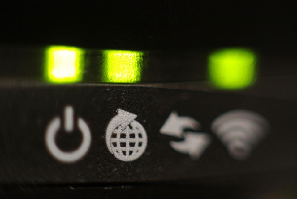Close-up of a broadband router's illuminated lights and indicator symbols.