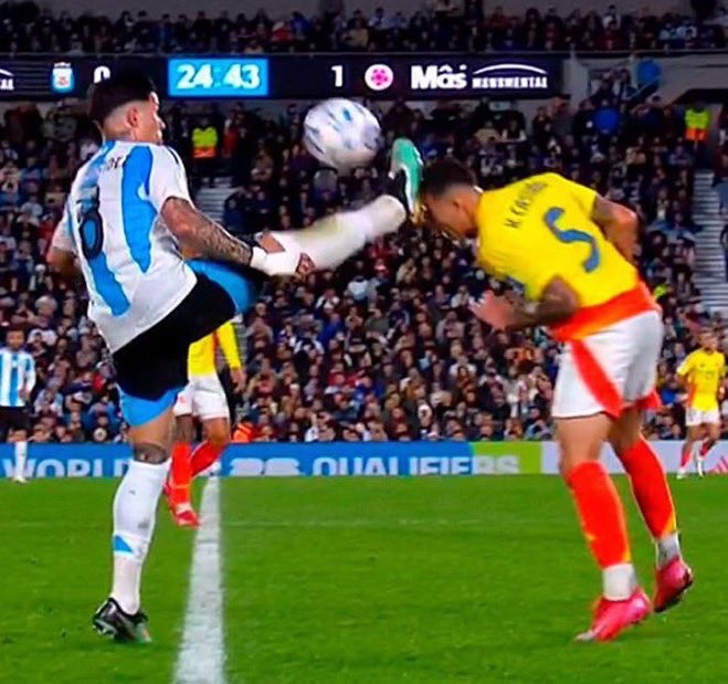 Soccer player kicking the ball into another player's face.