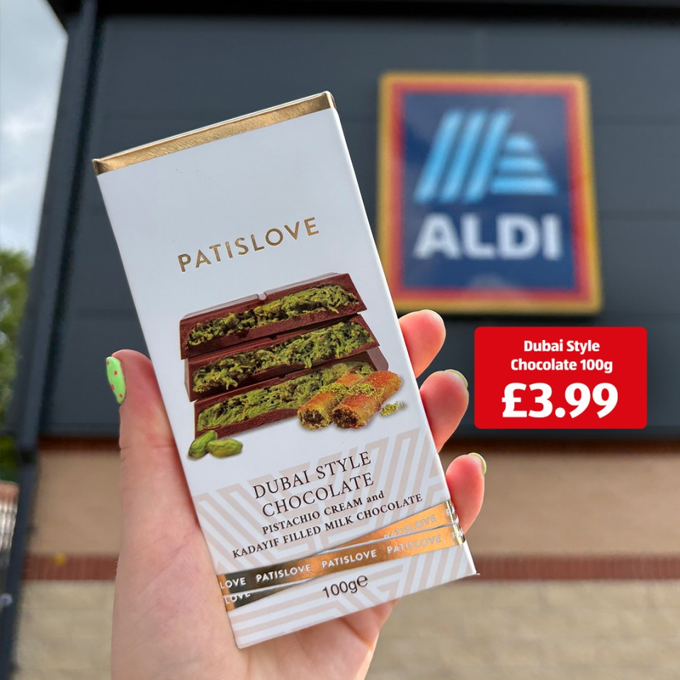 Hand holding a bar of Patislove Dubai Style Chocolate in front of an Aldi store.