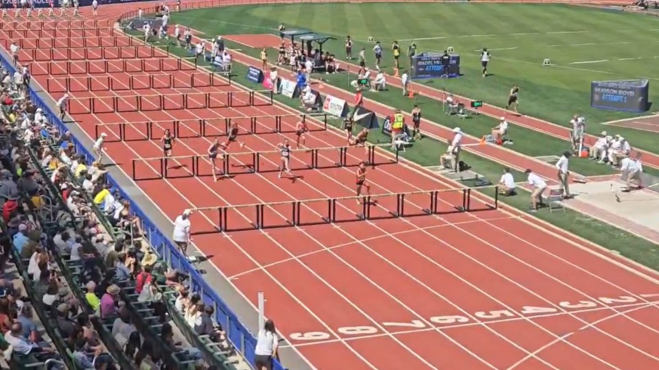 High school track athlete tripping on the final hurdle but winning first place.