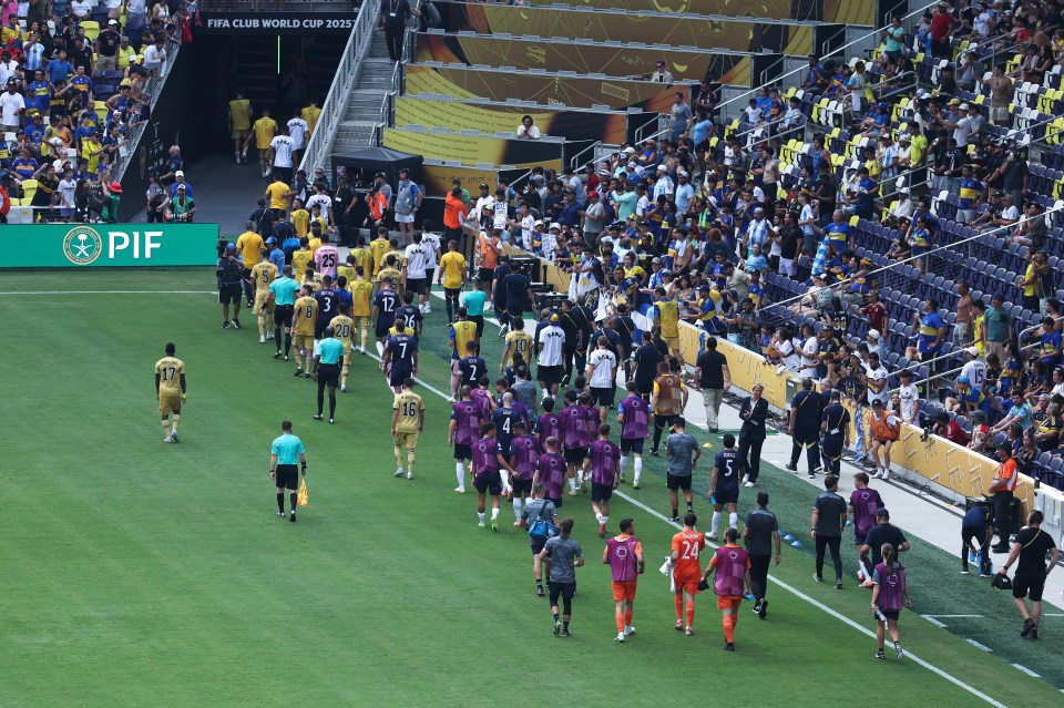 Soccer players from Auckland City FC and CA Boca Juniors leave the field after a weather delay.