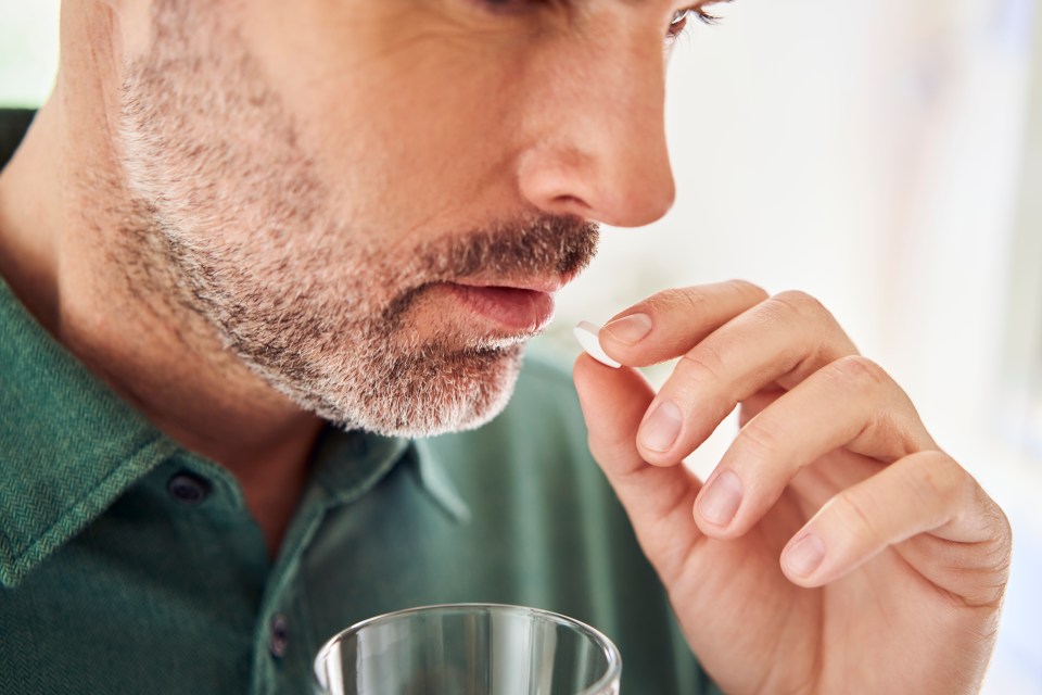 Close-up of a man taking a pill.