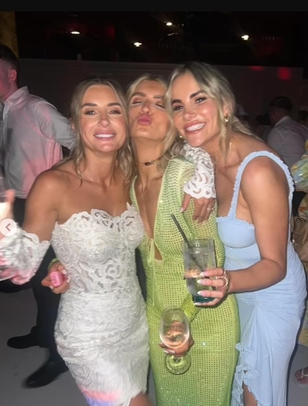 Three women at a wedding, one in a white dress, one in a lime green dress, and one in a light blue dress.