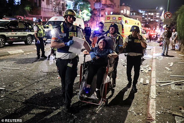 Rescue personnel evacuate a wounded woman at an impact site following missile attack from Iran on Israel, in Ramat Gan, Israel June 13