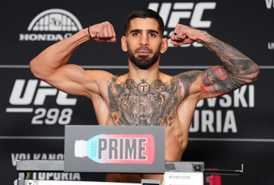 Ilia Topuria flexing his biceps at a UFC weigh-in.