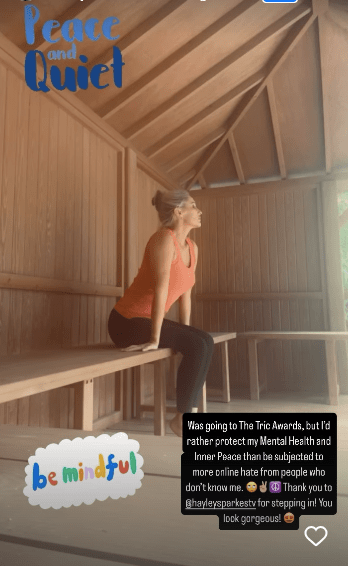 Woman sitting on a bench in a wooden structure, prioritizing mental health.