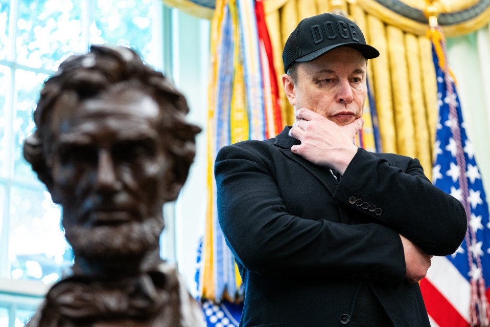 Elon Musk in the Oval Office wearing a black "DOGE" hat.
