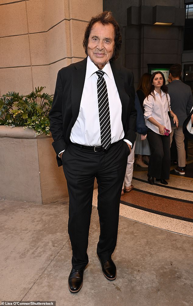 The legendary singer stepped out in a classic black suit with a white dress shirt, a black and white striped tie, black belt, black pants and black shoes