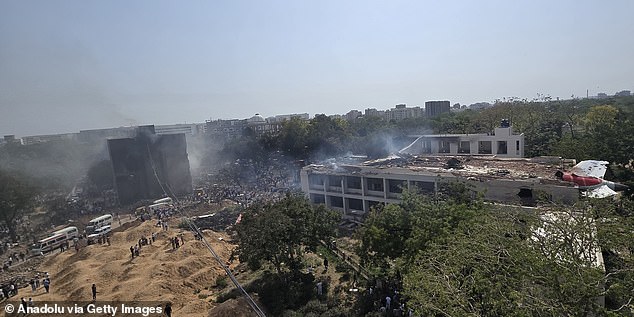 This wide angle shot shows the entire scene of the plane crash. The tail and parts of the fuselage are seen on the building to the right, with the bulk of the jet having smashed into the buildings further on