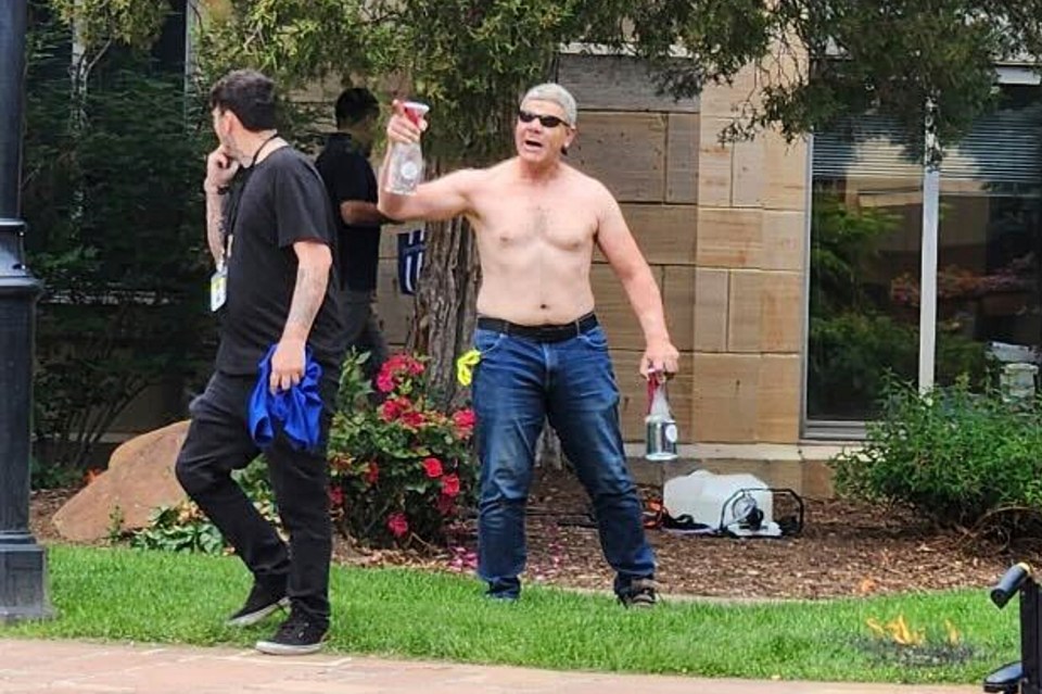 Photo of a shirtless man holding bottles and a spray bottle, appearing to be involved in a confrontation.