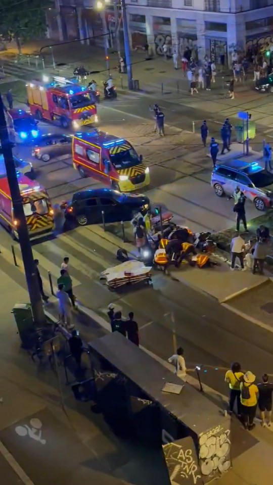 Aerial view of a car accident scene with emergency responders and bystanders.