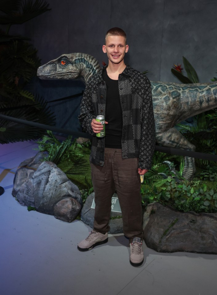 A man stands next to a Velociraptor at the grand opening of Jurassic World: The Experience in London.